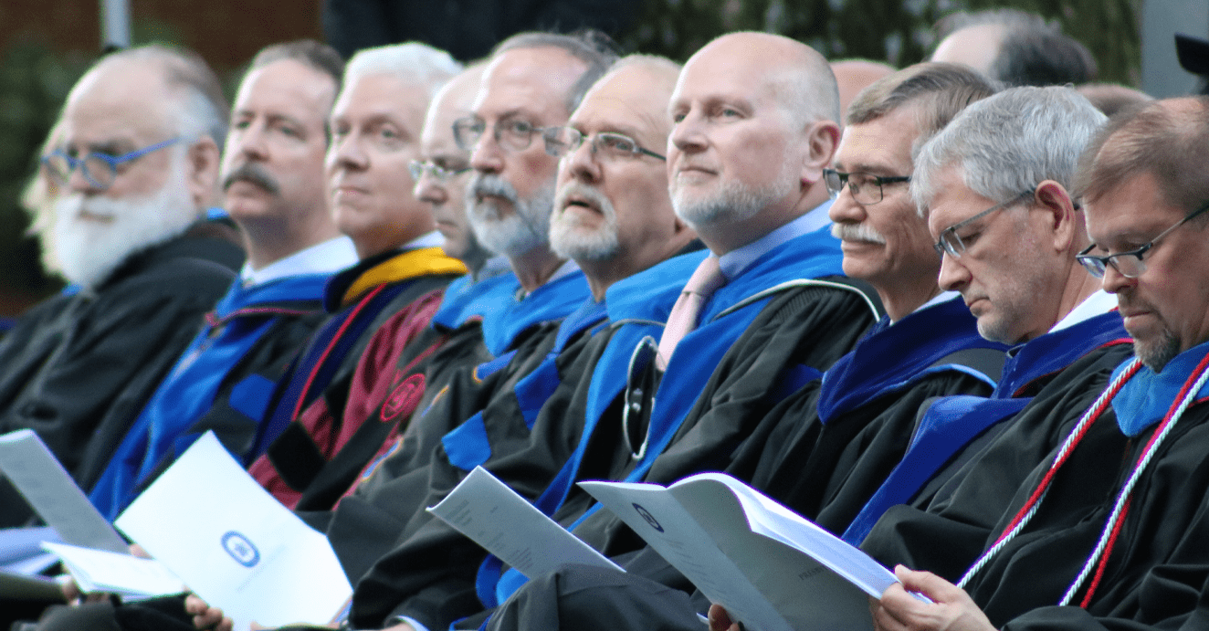 PC professors in academic regalia sitting at the ceremony