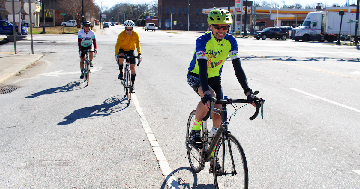 Presbyterian College English professor Dr. Justin Brent leads a pack of cyclists through the City of Clinton's busiest intersection.