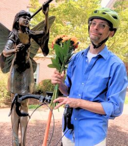 Dr. Justin Brent wearing a bike helmet holding flowers