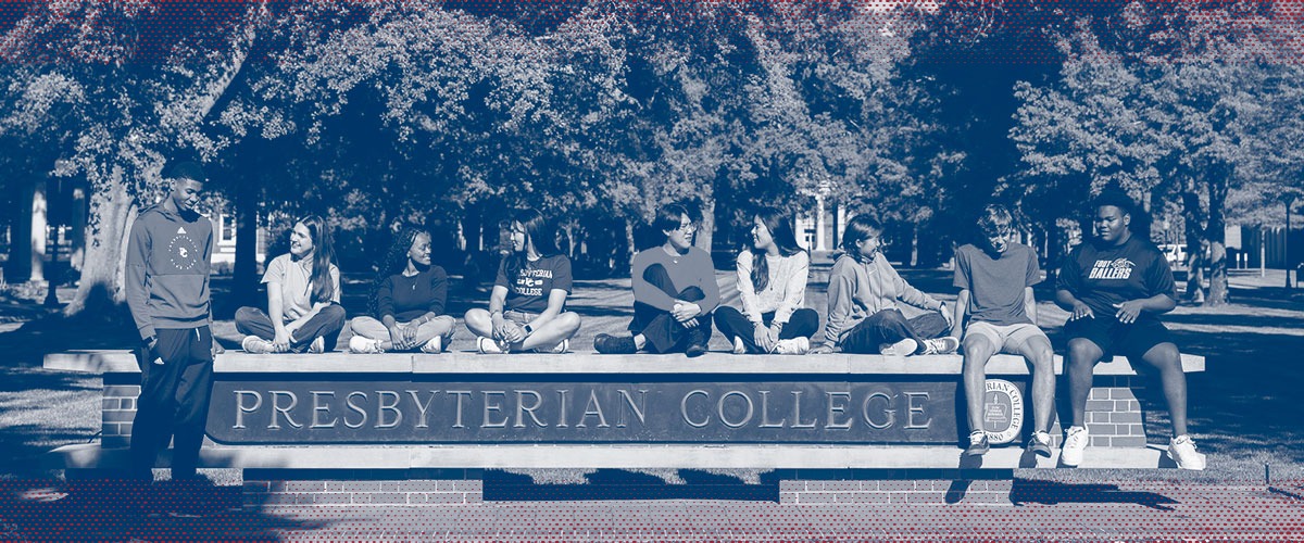 A group of students sitting on Presbyterian College sign with one standing to the left