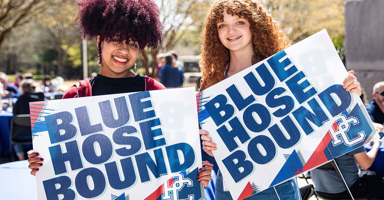 two girls holding up PC Blue Hose Bound yard signs