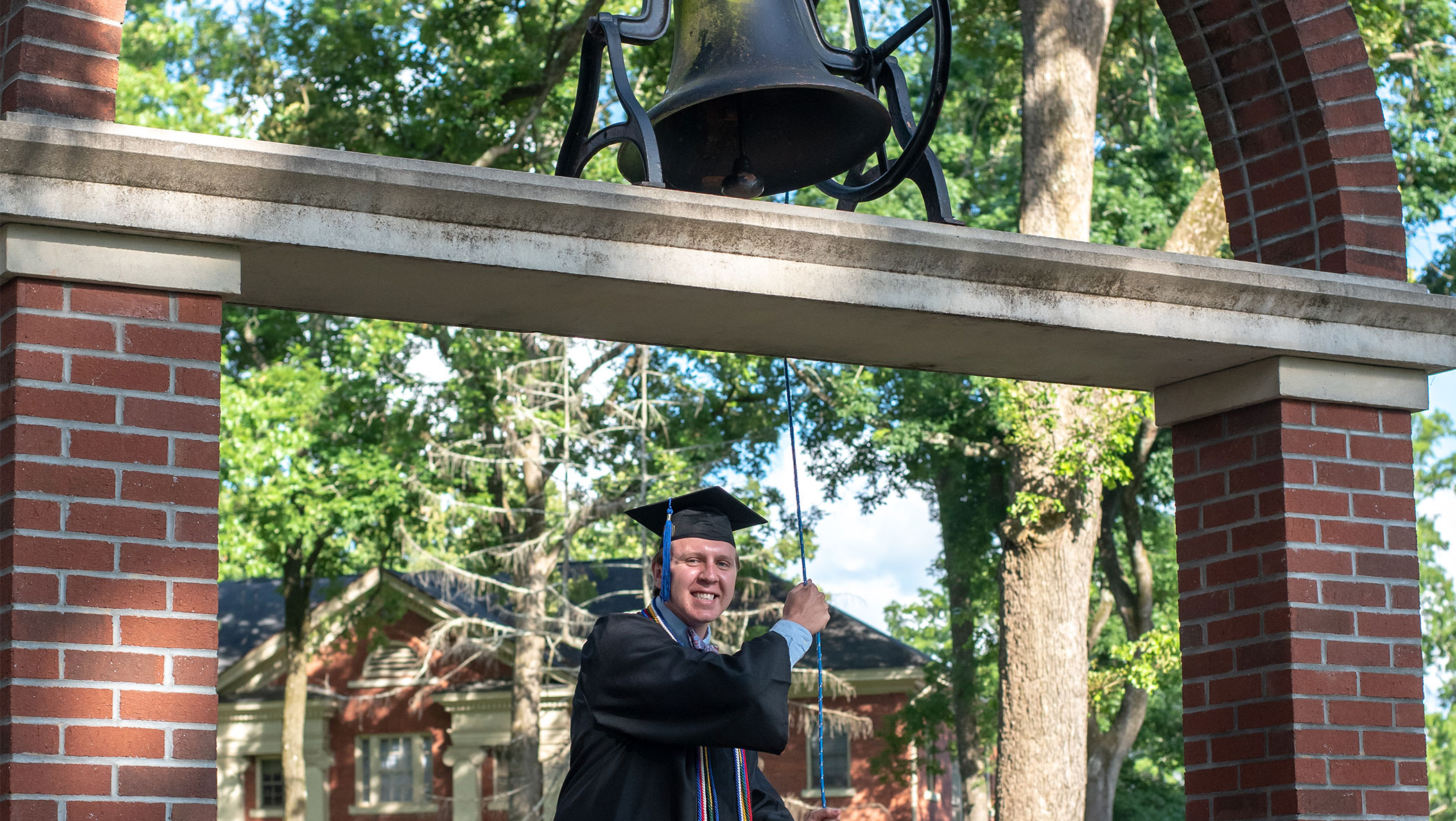 Student in the academic regalia ringing a bell