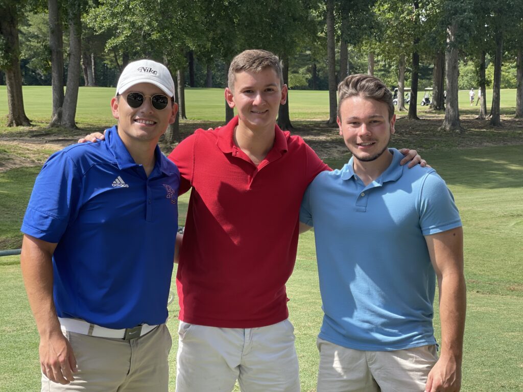 Three gentlemen on the golf field smile for a shot