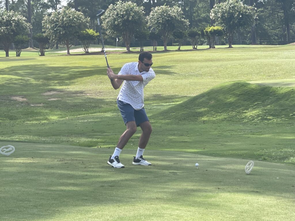 A man is about to hit the ball with a golf club in a tournament