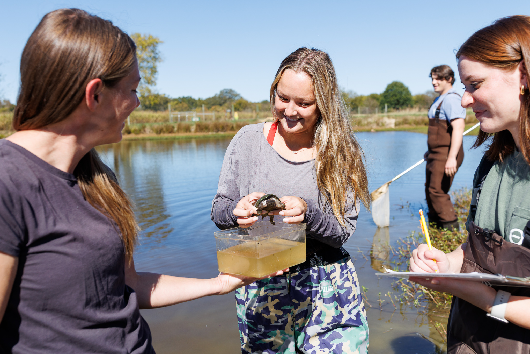 Presbyterian College Biology student holding a turtle at a lake.