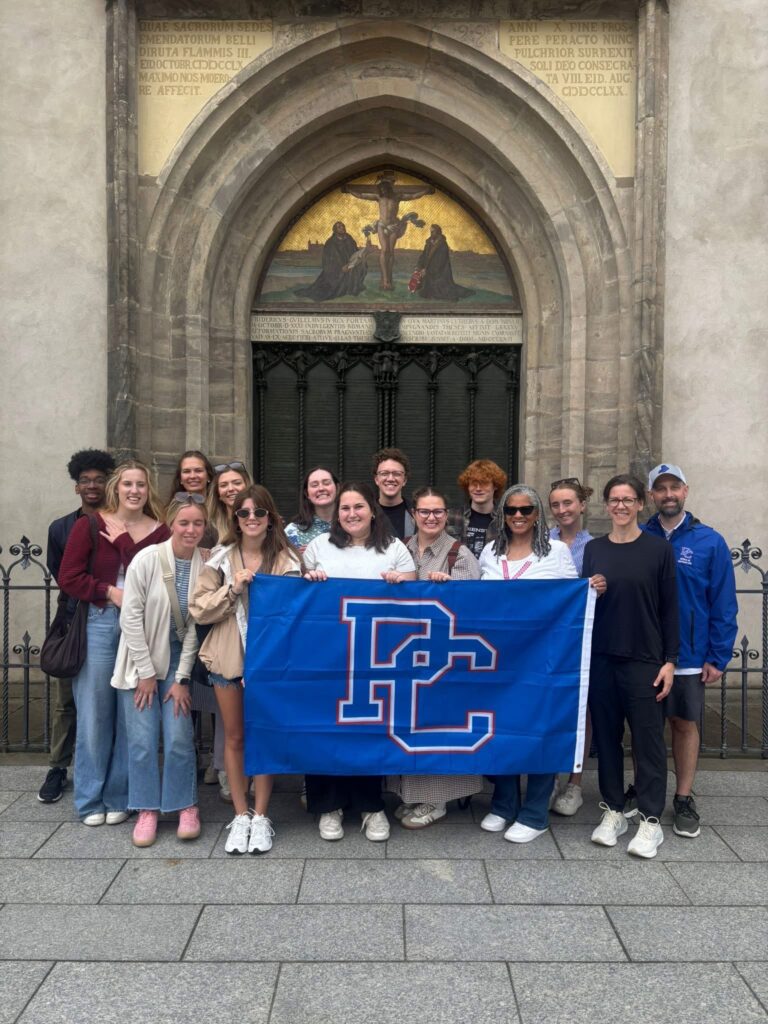 Celtic Cross students posing with a Presbyterian College flag in Germany