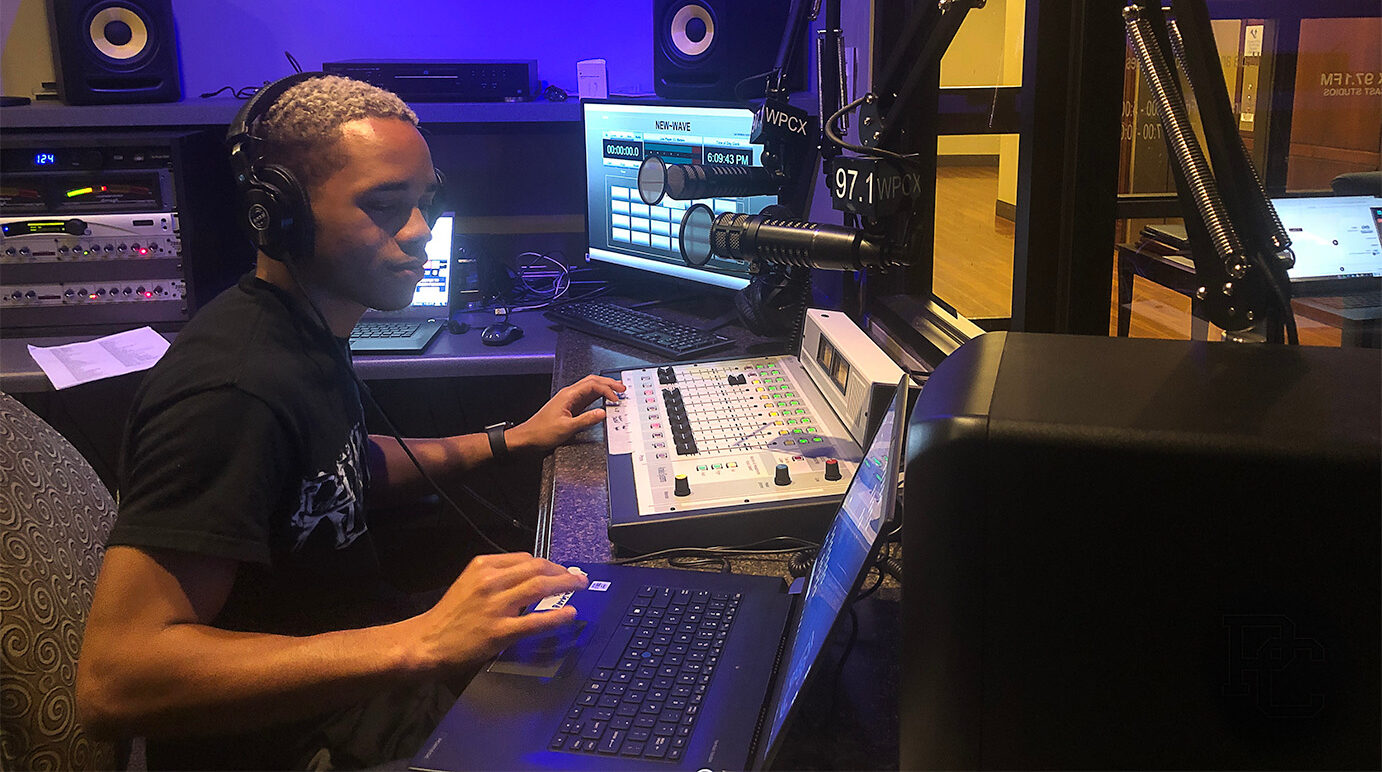 PC student Khalid sitting at a desk for the WPCX, a student run radio station