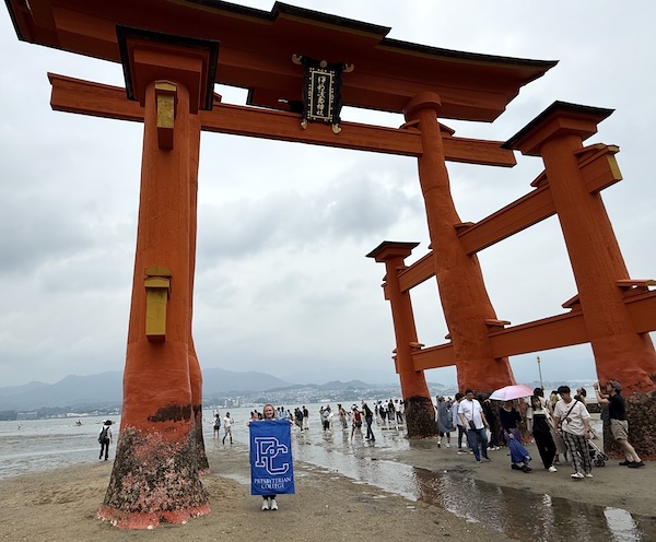 Dr. Brooke Spatta with the Presbyterian College flag in front of the famed tore at the Itsukushima Shrine on Miyajima Island in Japan.