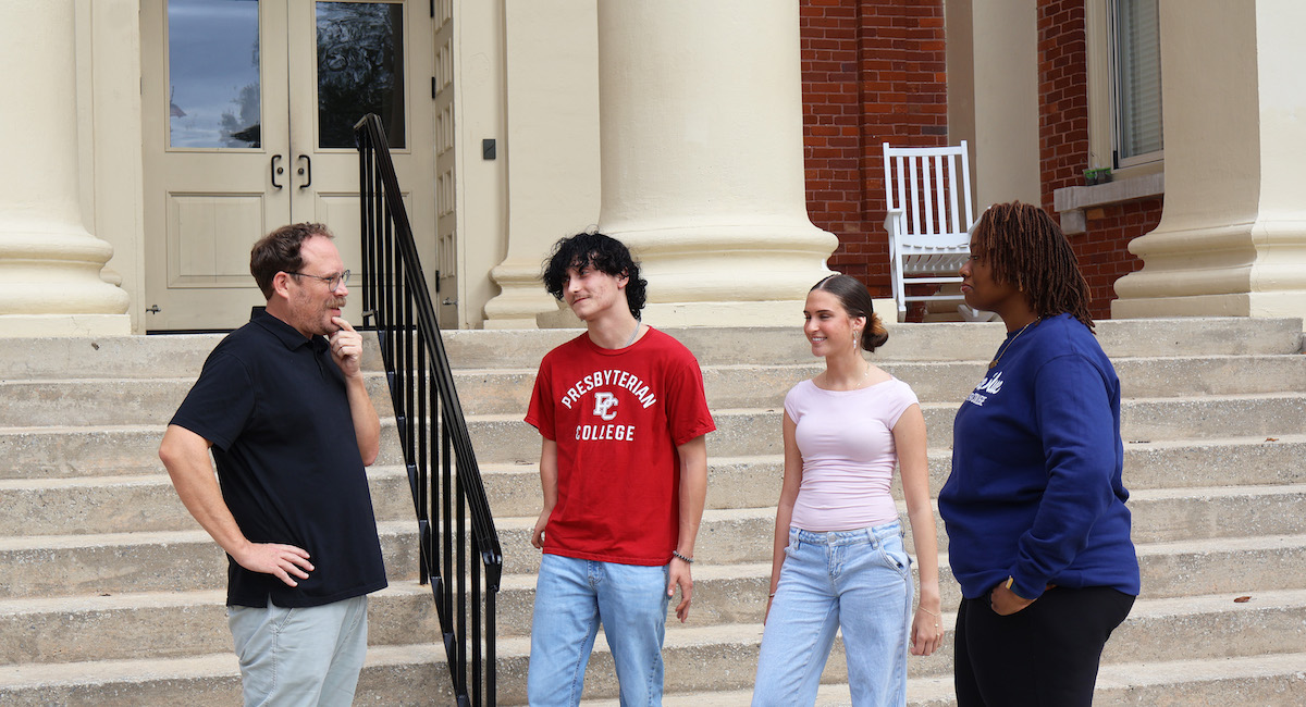 Political science professor Dr. Ben Bailey chatting with the new Service Entrepreneurship Competition winners -- Drayven Hallman, Sarah Danbury, and Anya Mack.