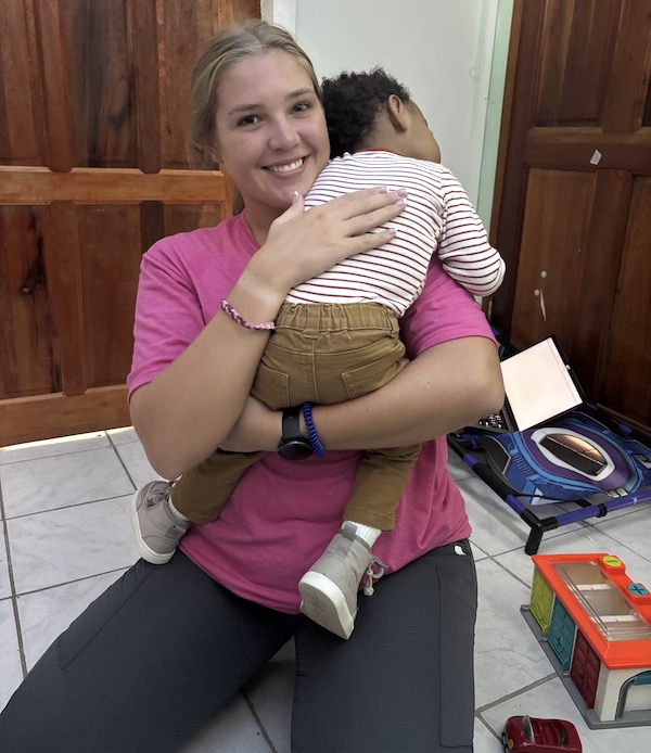 A PC OT student holds a tired child during her mission trip in Belize.
