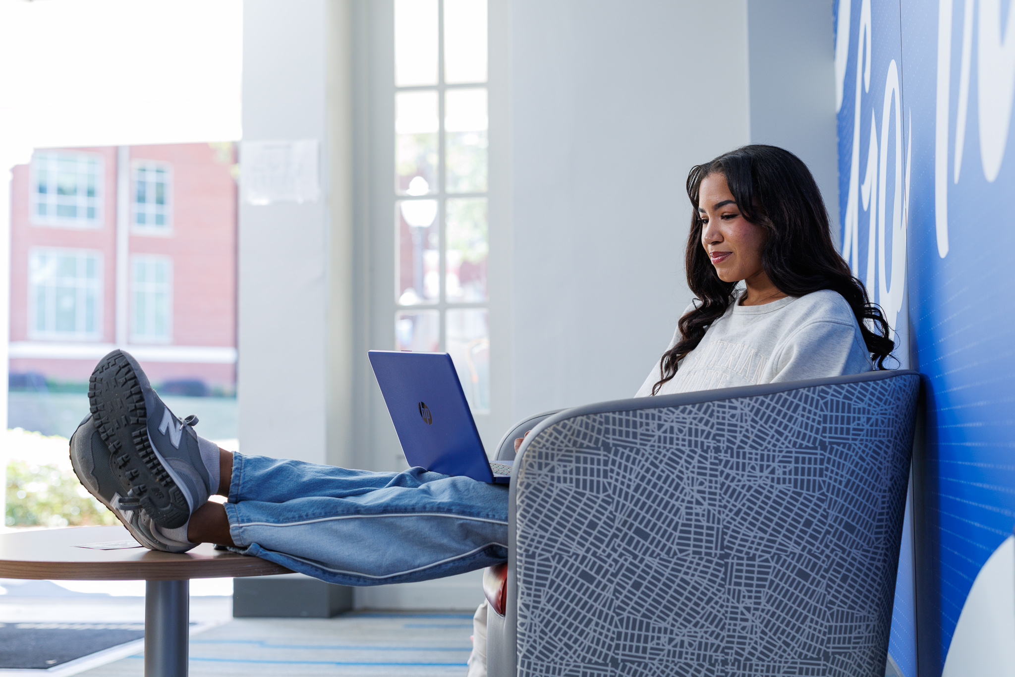 Presbyterian College student sitting on a chair with her laptop.