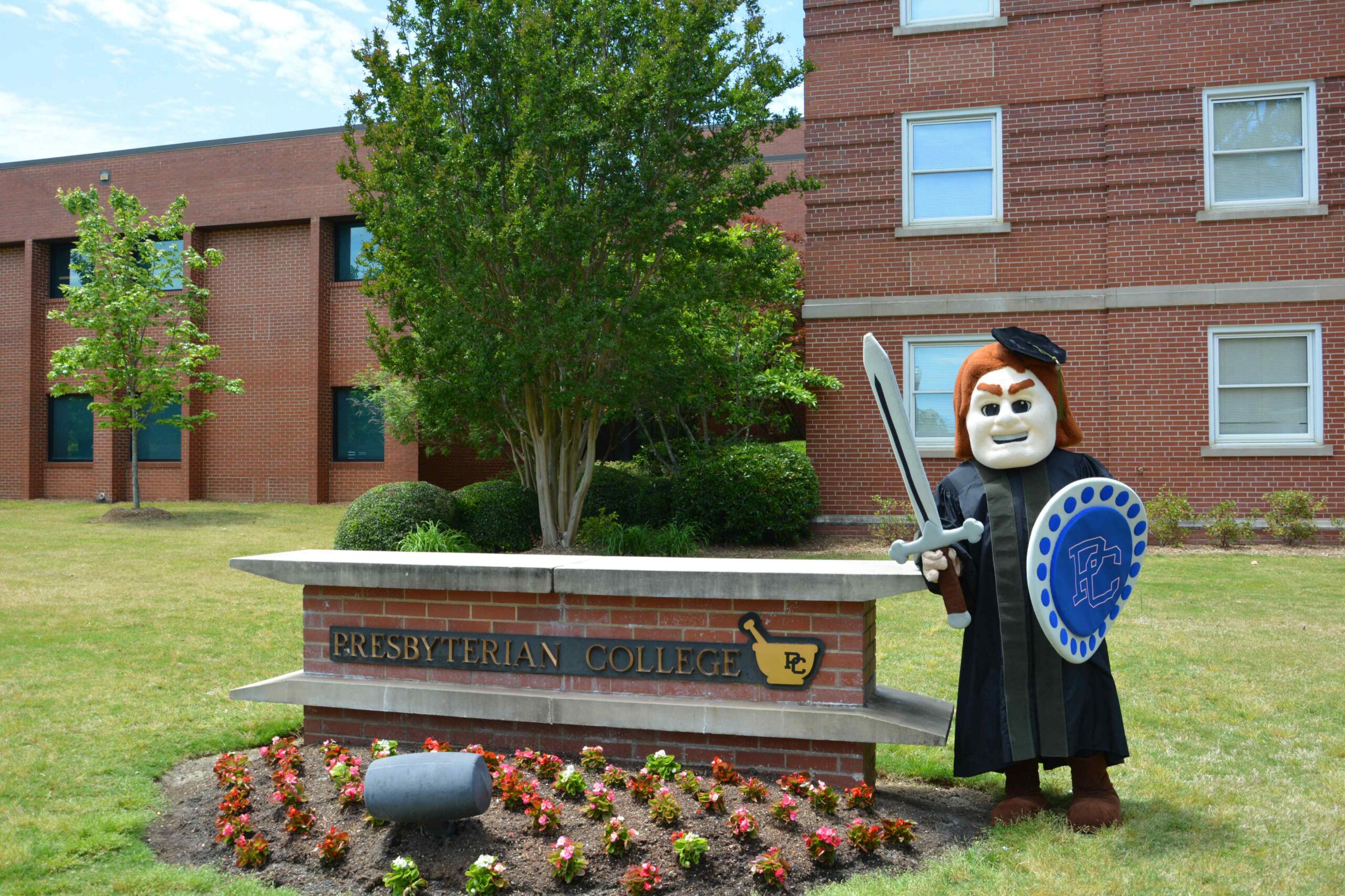 Scotty the Scotsman in graduation cap and gown at the Pharmacy School Sign