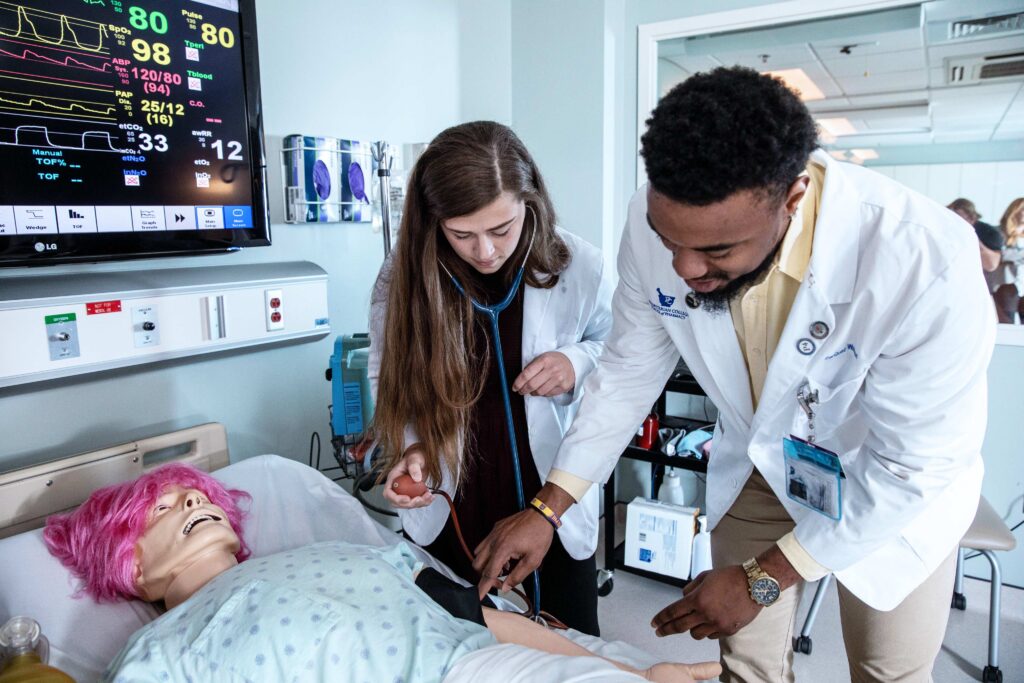 Pharmacy students practicing on a fake patient.
