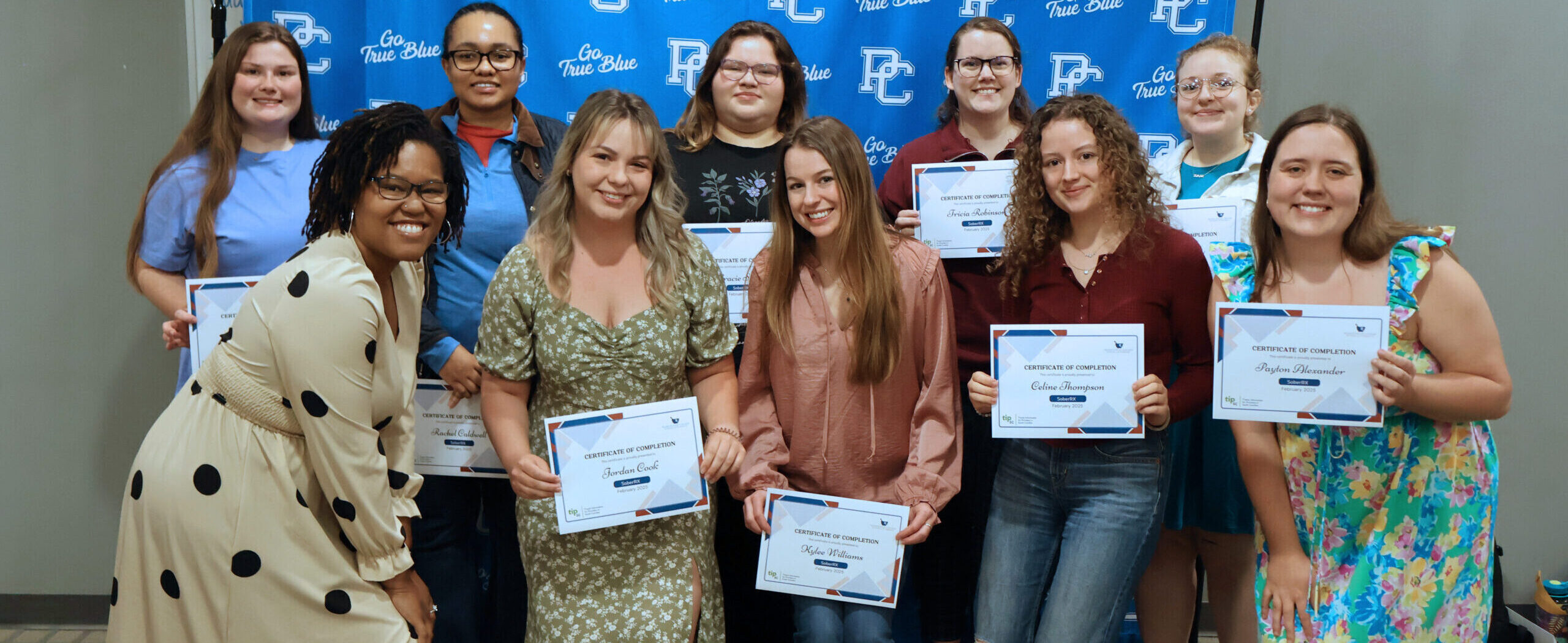 Students pose for a picture after receiving certificates of completion.