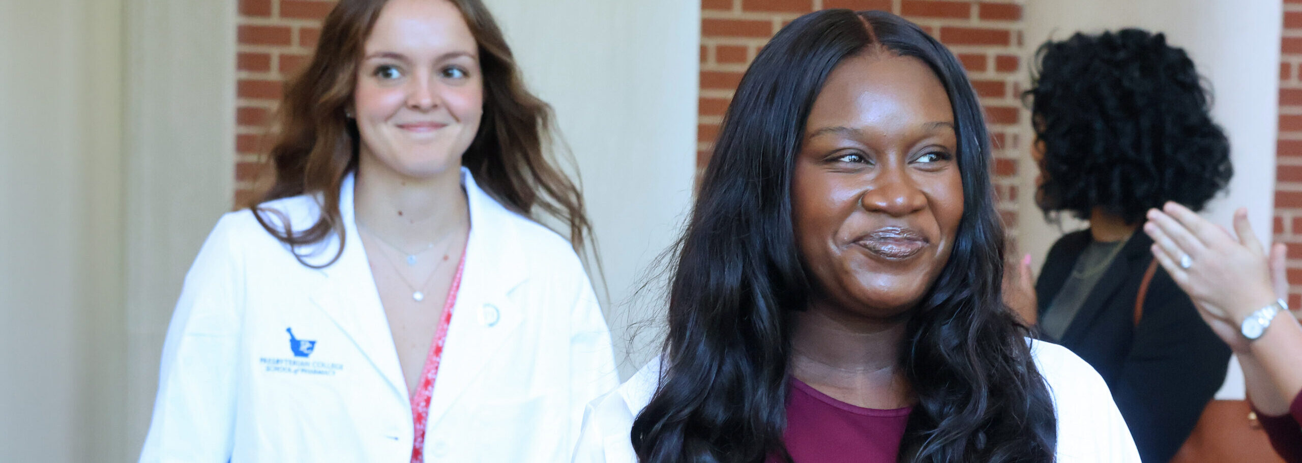Pharmacy student smiles after receiving her white coat.
