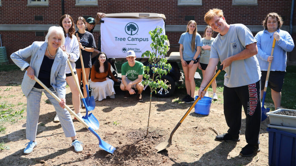 PC president Dr. Anita Gustafson plans a tree with students during the campus' celebration of Earth Day.