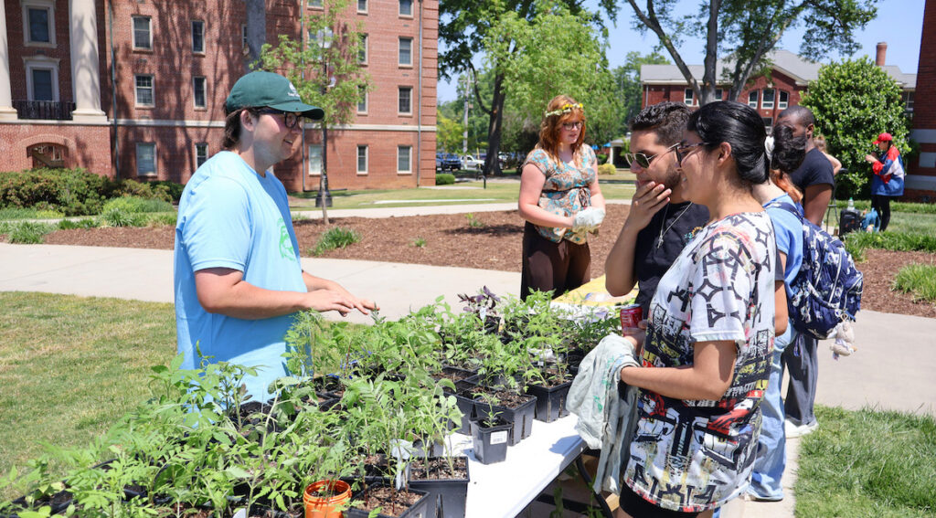 PC sophomore Ezra Marks gives away plants he grew in the college's greenhouse during Earth Day.