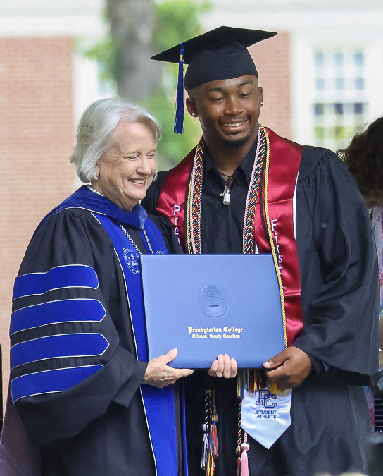 PC president Dr. Anita Gustafson presents a diploma to a new graduate of the liberal arts college.