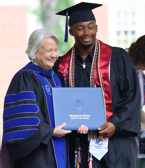 PC president Dr. Anita Gustafson presents a diploma to a new graduate of the liberal arts college.