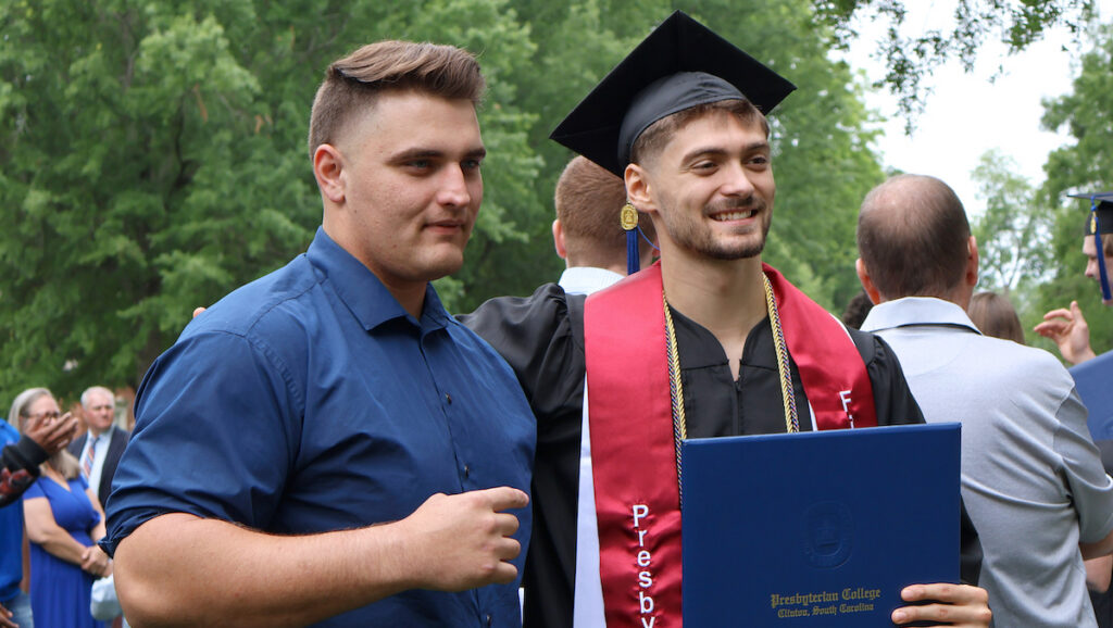 A proud first-generation college graduate poses for pictures following Presbyterian College's commencement celebrating the liberal arts.