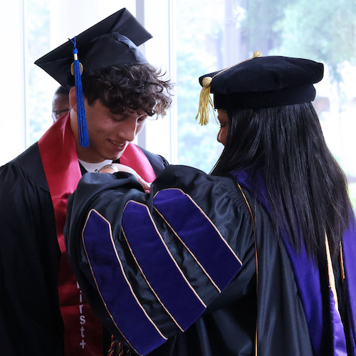 A PC graduating senior is granted cords and a stole reflecting his journey of perseverance and resilience during the 2026 Mosaic Ceremony.