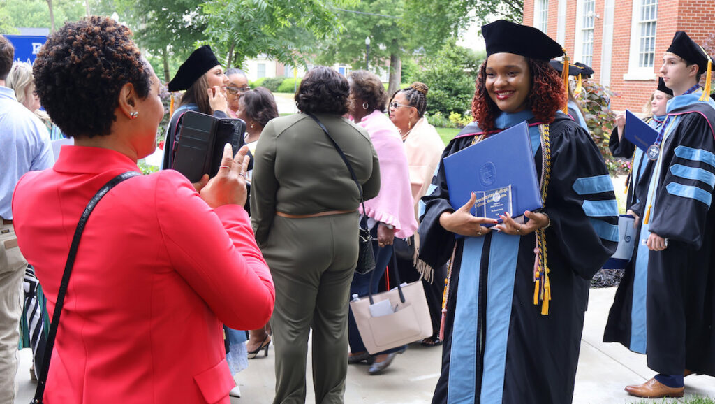 A proud family member photographs a new doctor of occupational therapy after her commencement and hooding ceremony at Presbyterian College.