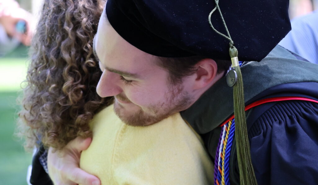 A new doctor of pharmacy gets a heartfelt hug from family following his hooding ceremony at Presbyterian College.