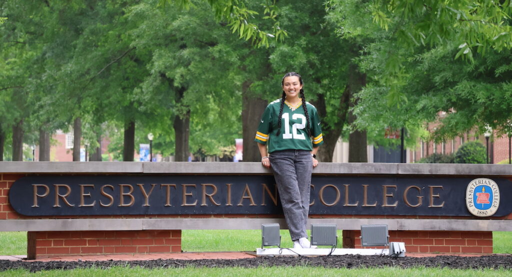 Vanessa Palisin, a recent graduate of Presbyterian College, poses on the college entrance sign in a Green Bay Packers jersey in anticipation of her internship with the NFL franchise.