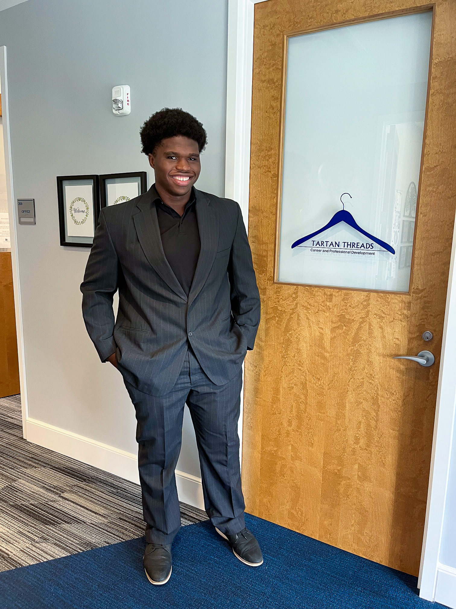 Student standing in a suit in front of Tartan Threads at Presbyterian College
