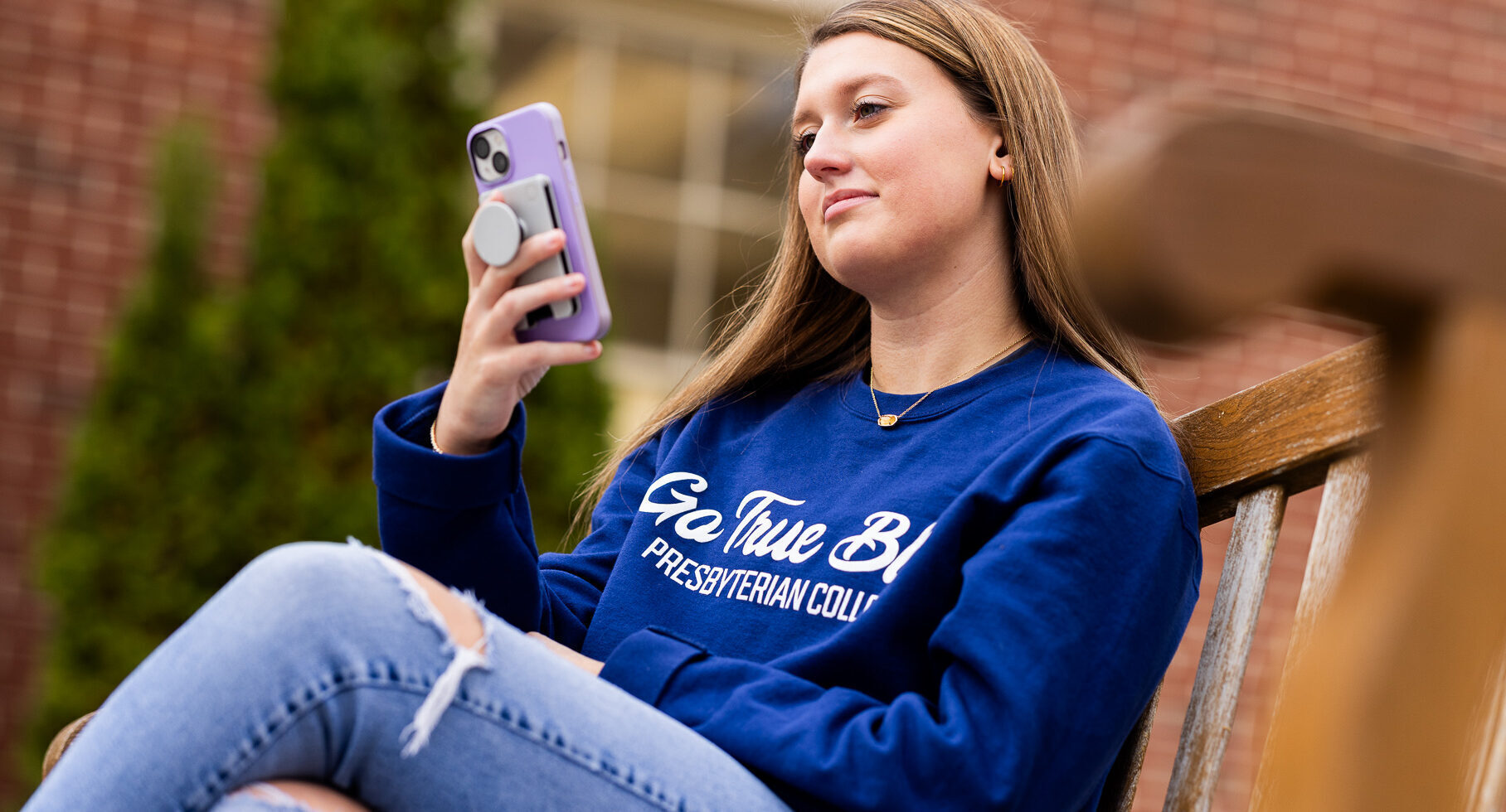Student sitting on bench and looking at phone