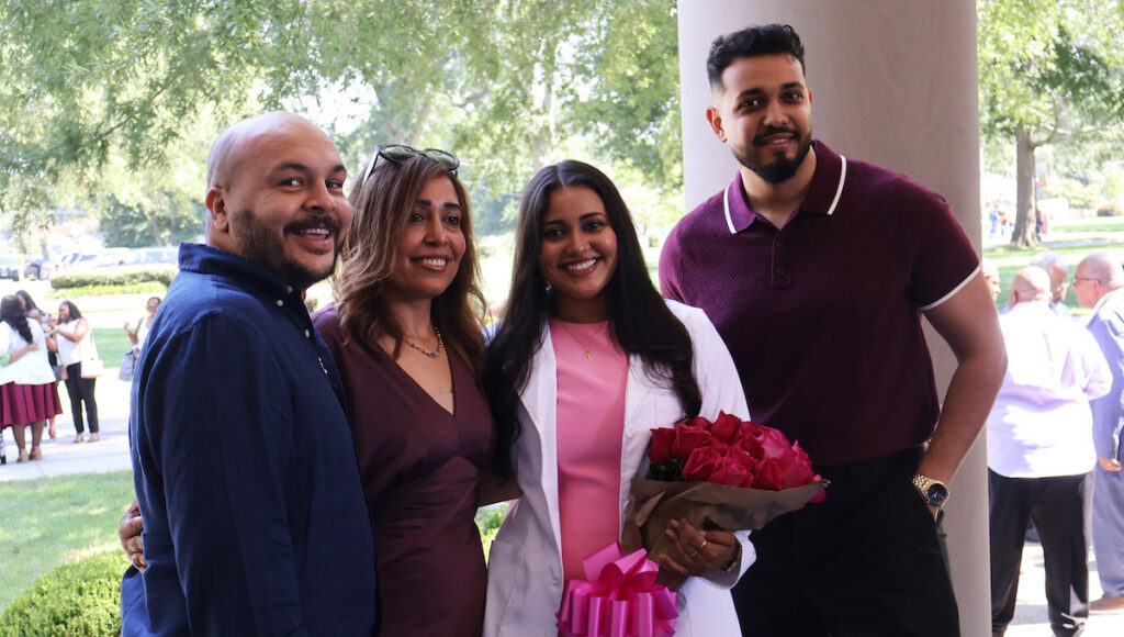 A new P1 wears her white coat and celebrates with family following the 2026 White Coat ceremony.