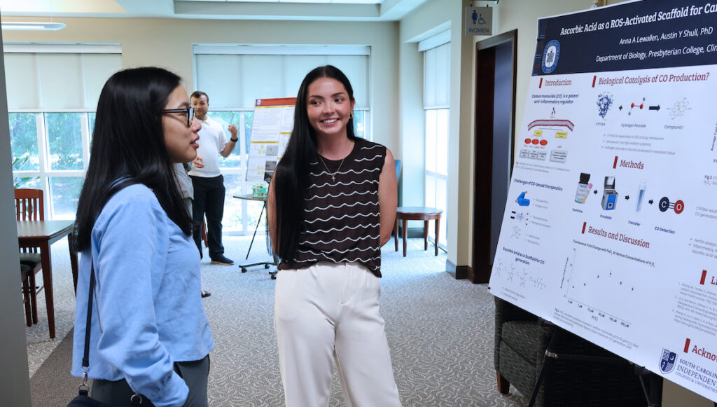 PC student Anna Lewallen (right) discusses her biology research to chemistry professor Dr. Kimberly De La Cruz during the 2026 Summer Research Symposium.