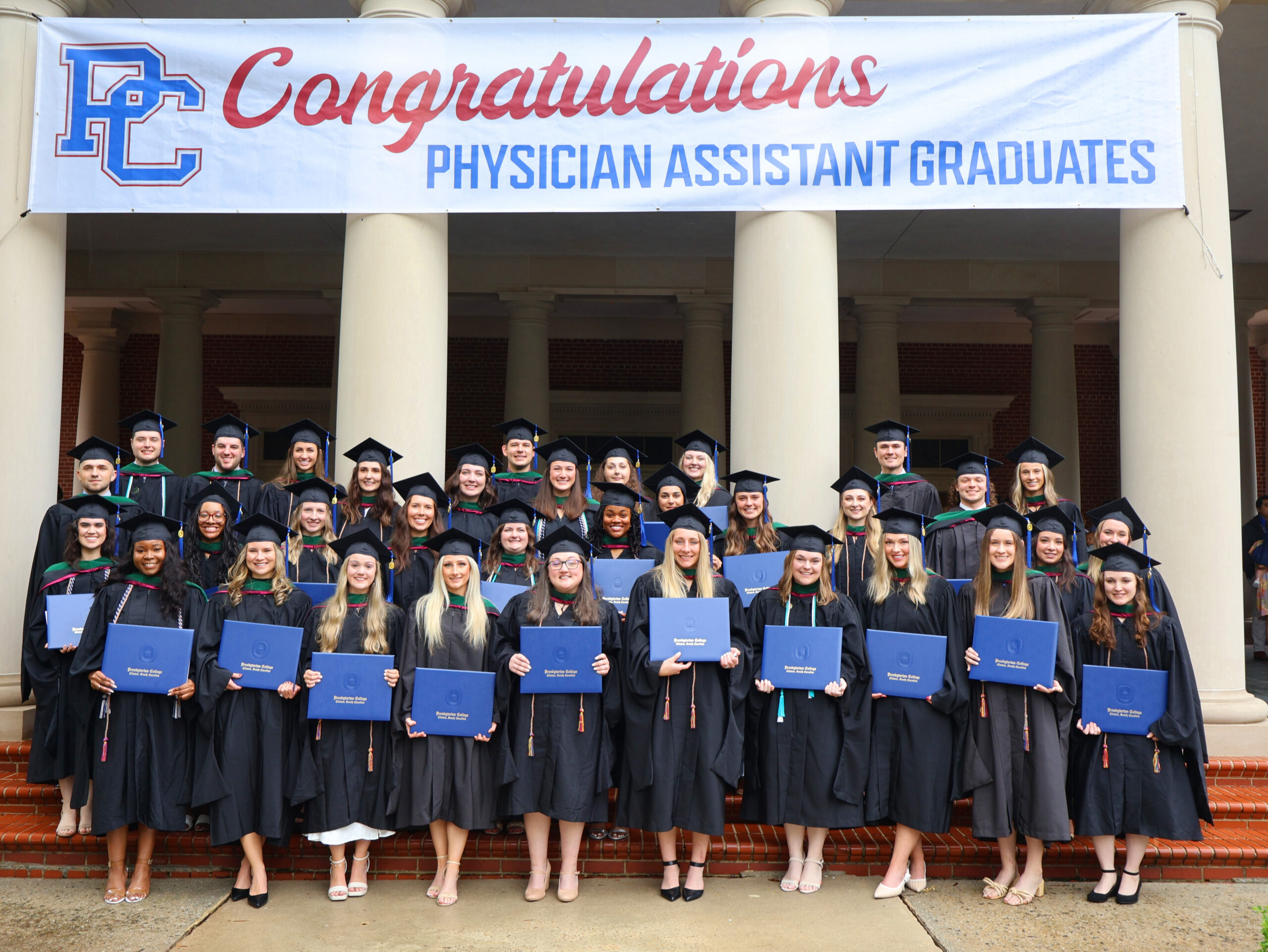 Physician Assistant graduates standing with their degrees