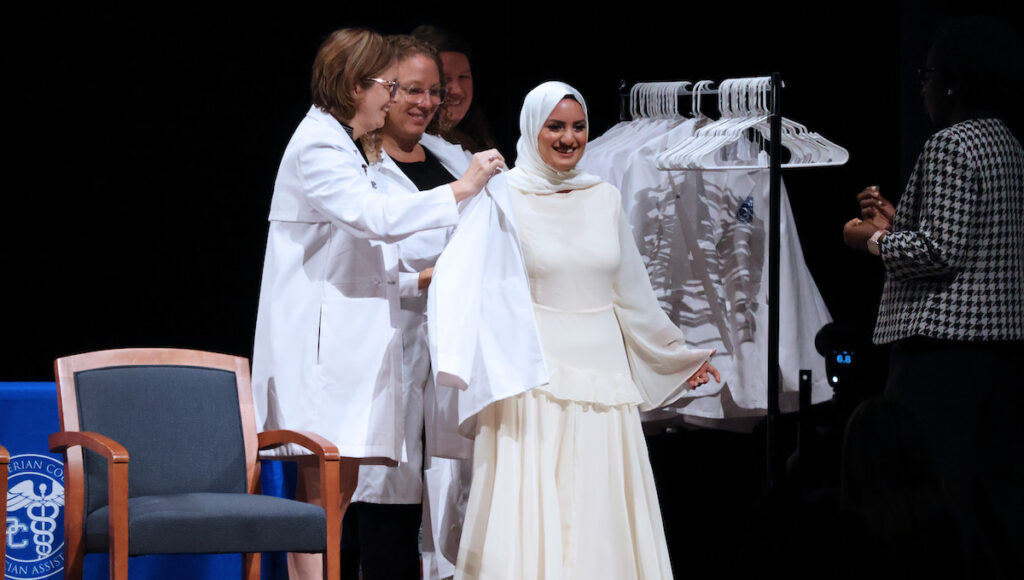 A student receives her white coat at the 2026 White Coat Ceremony for the PC Physician Assistant Program.
